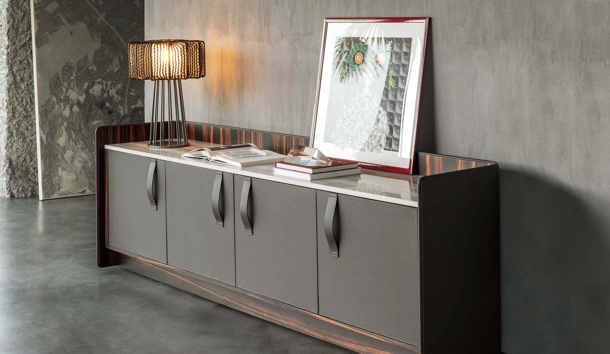 Madia Gentleman con struttura in legno multistrato curvato rivestito esternamente in pelle grigia, internamente in ebano con top in marmo di Flou